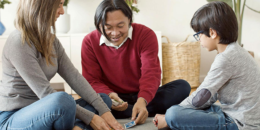 a family of three playing a card game in a living room
