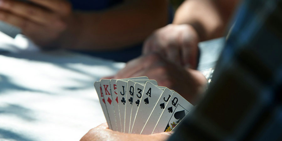 close up view of three people, one person holding several playing cards